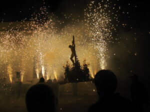 Foto de las fiestas con fuegos artificiales y una figura de la cruz.